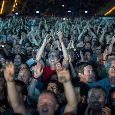 Das Bild zeigt eine Menge feiernder Fans bei einem Musikkonzert.