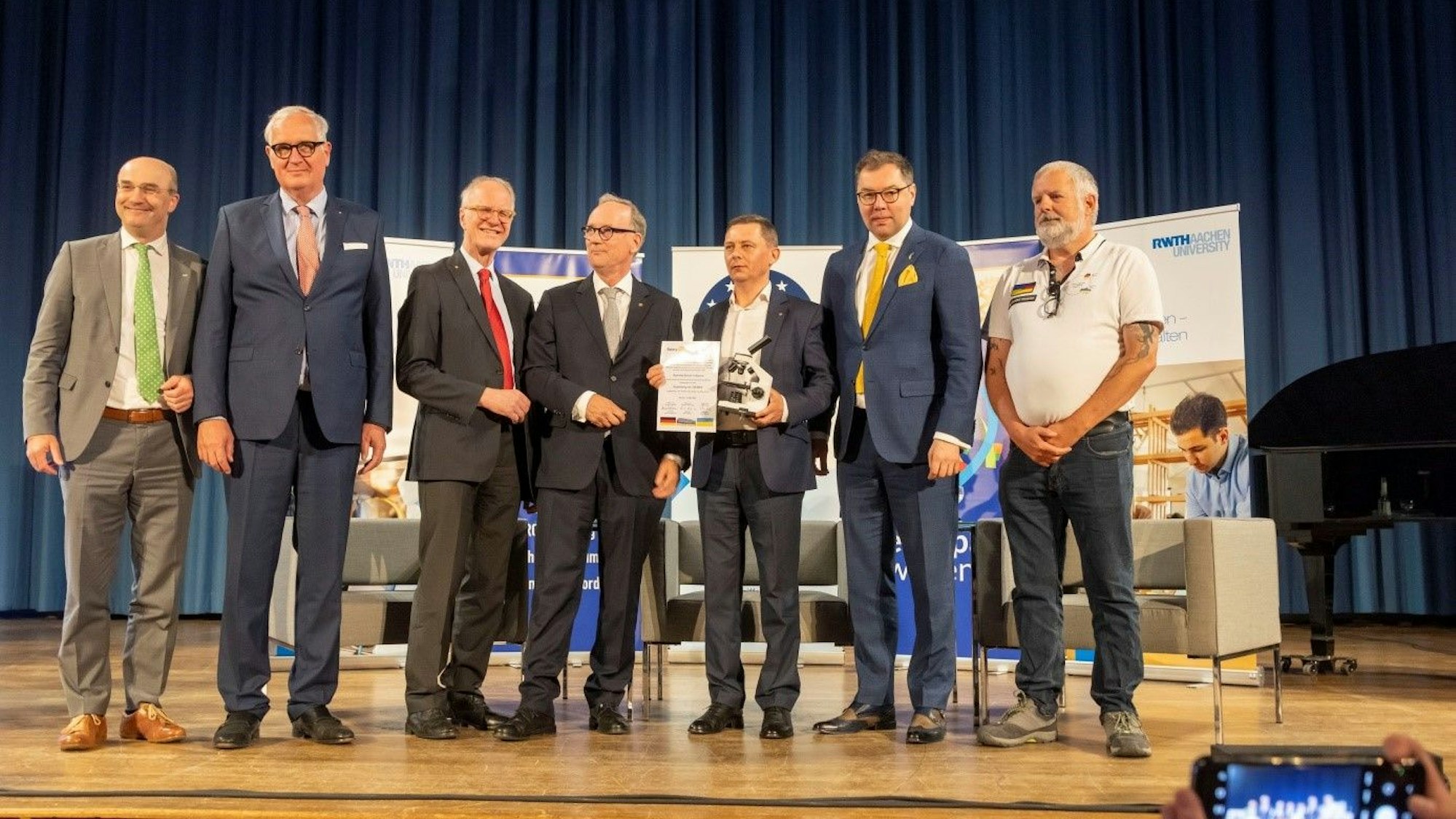 Männer stehen auf einer Bühne.