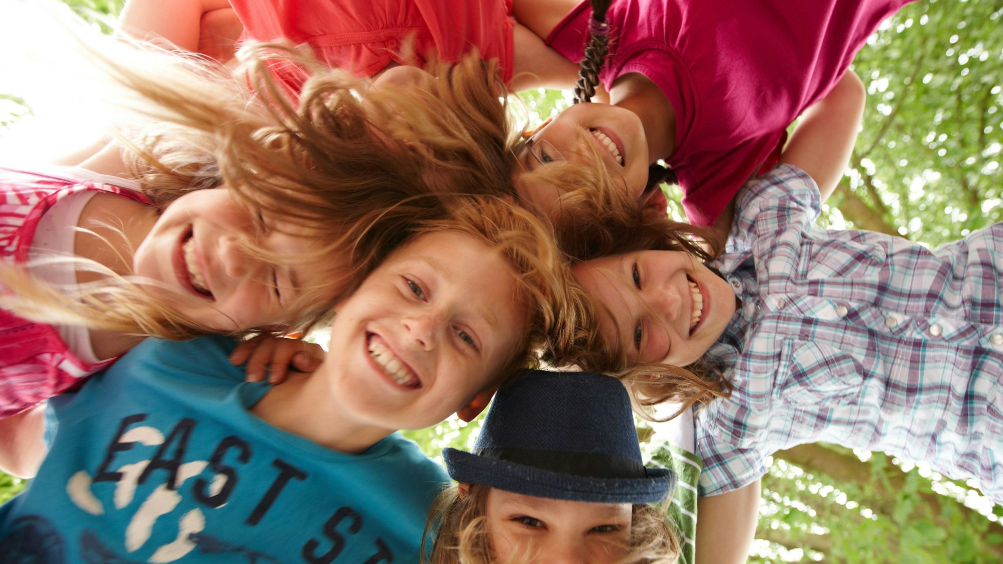 Sechs Jungen und Mädchen stehen im Kreis und halten die Köpfe aneinander.