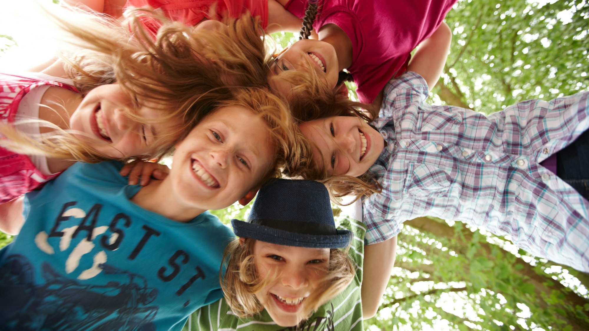 Kinder zeigen ihre Köpfe von oben in die Kamera.