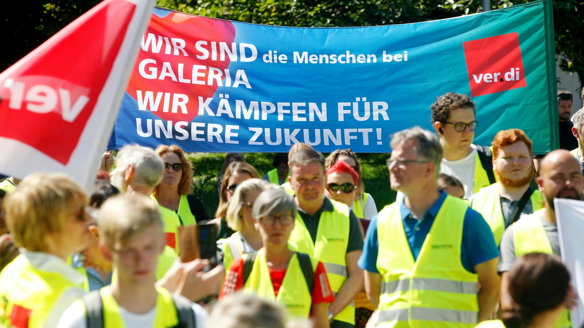 09.06.2023, Nordrhein-Westfalen, Essen: Mitarbeiter von Galeria Karstadt Kaufhof demonstrieren mit einem Plakat «Wir sind die Menschen bei Galeria - Wir kämpfen für unsere Zuknft».