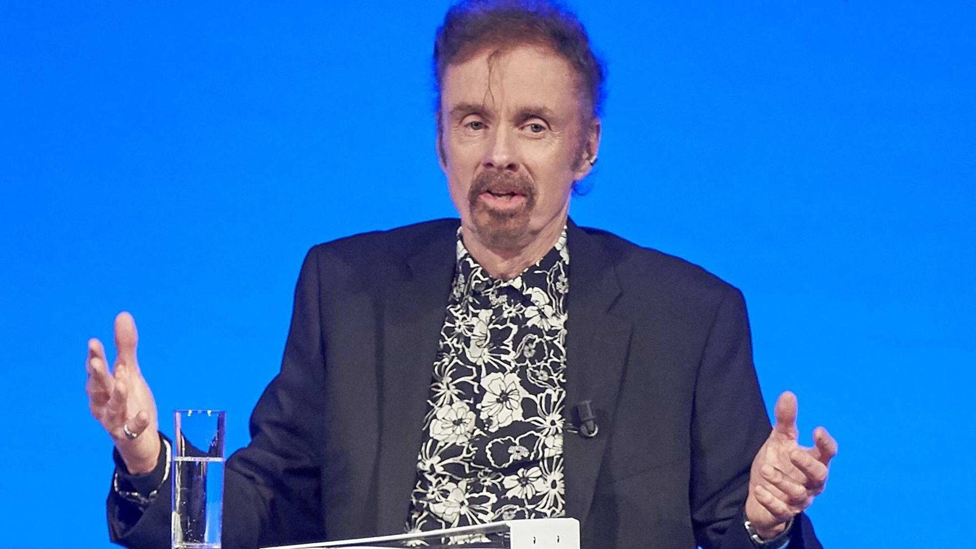 T. C. Boyle bei einer Lesung mit schwarz-weiß geblümten Hemd.