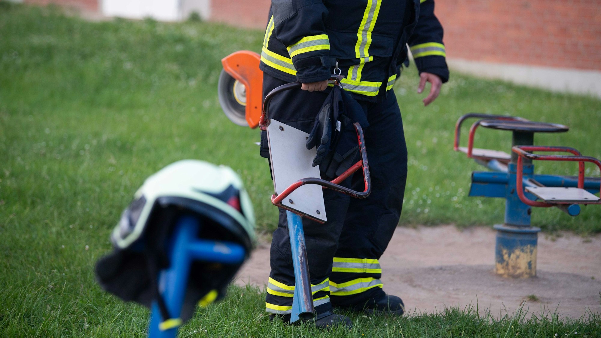 Ein Zülpicher Feuerwehrmann trägt den abgetrennten Teil des Spielgeräts vom Spielplatz in Wichterich.