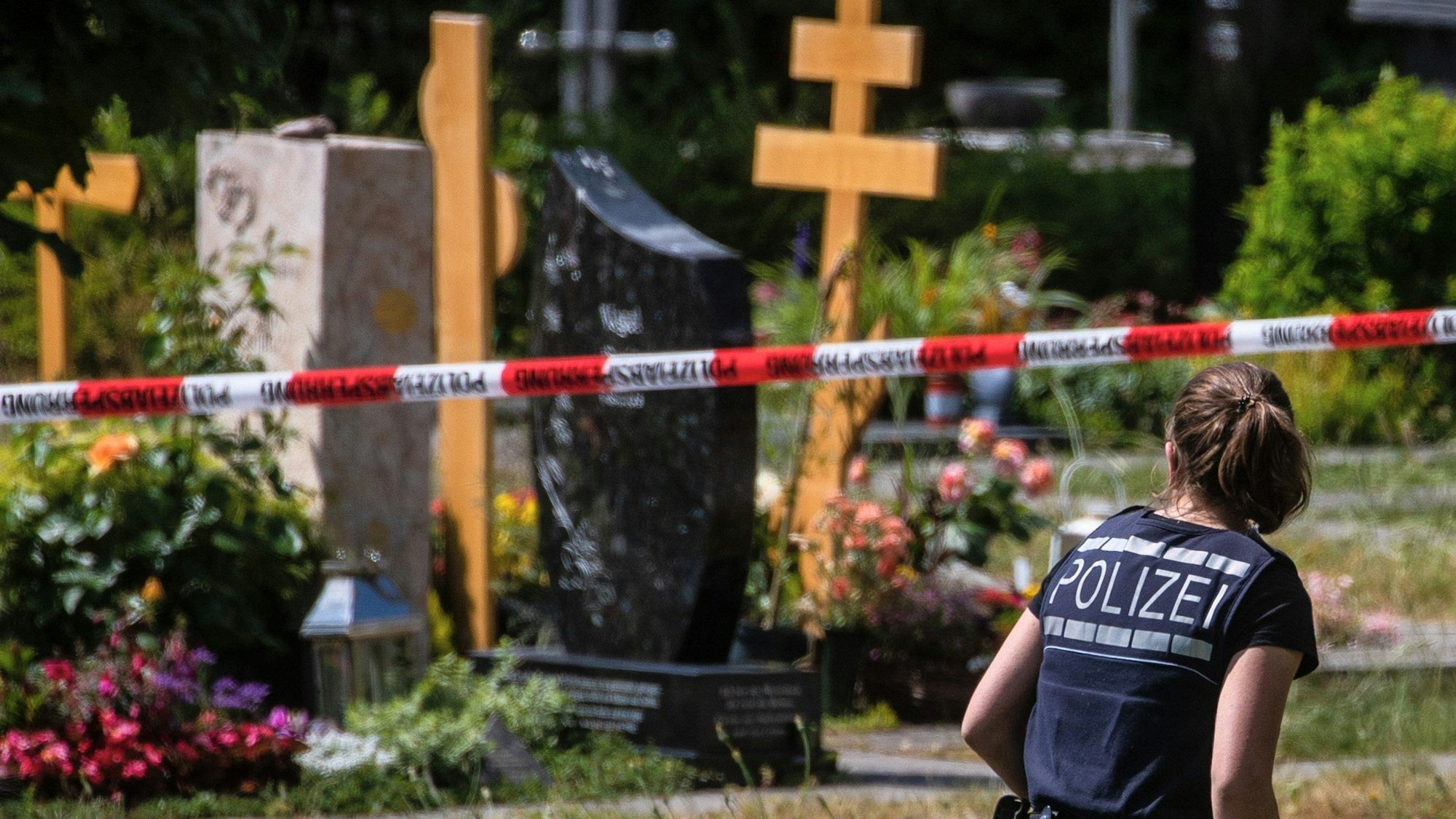 Eine Polizistin geht über den abgesperrten Teil an einem Tatort auf einem Friedhof in Altbach.