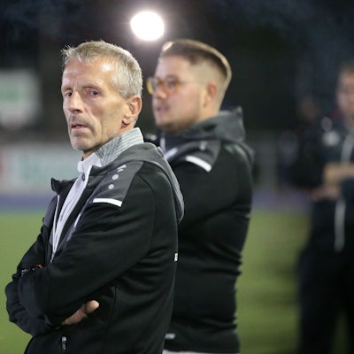 Ein Trainer steht am Rand eines Fußballfeldes.