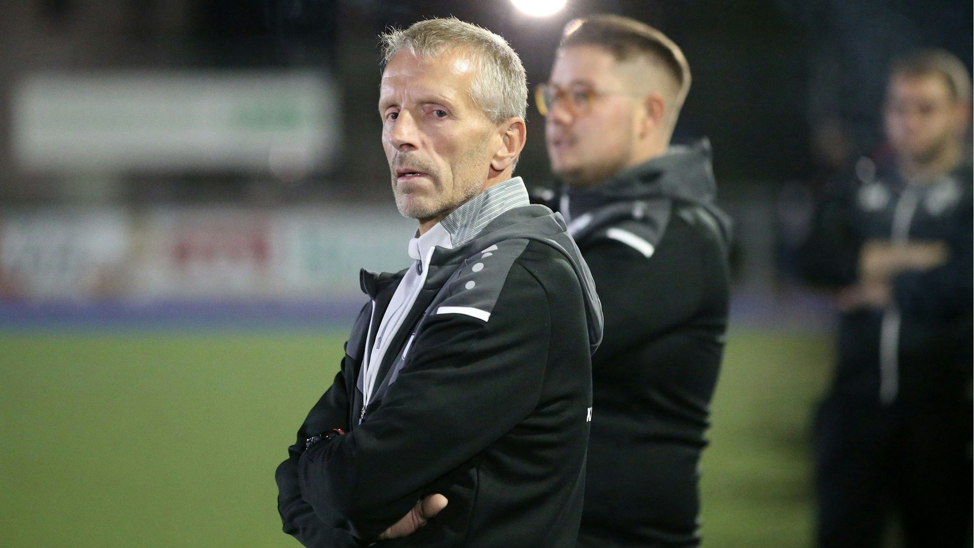 Ein Trainer steht am Rand eines Fußballfeldes.