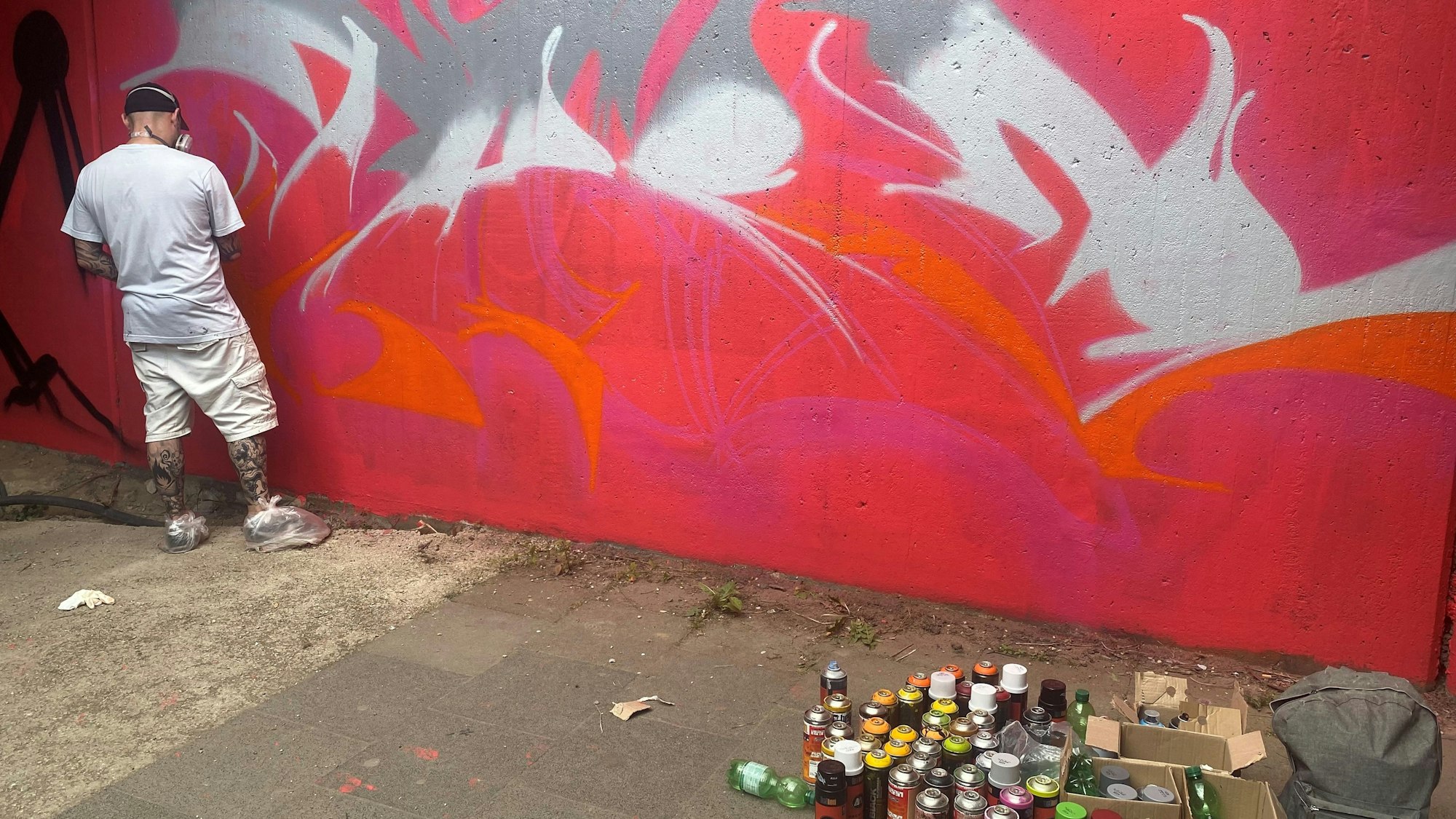 Sprayer One Take vor einer Graffiti-Wand.