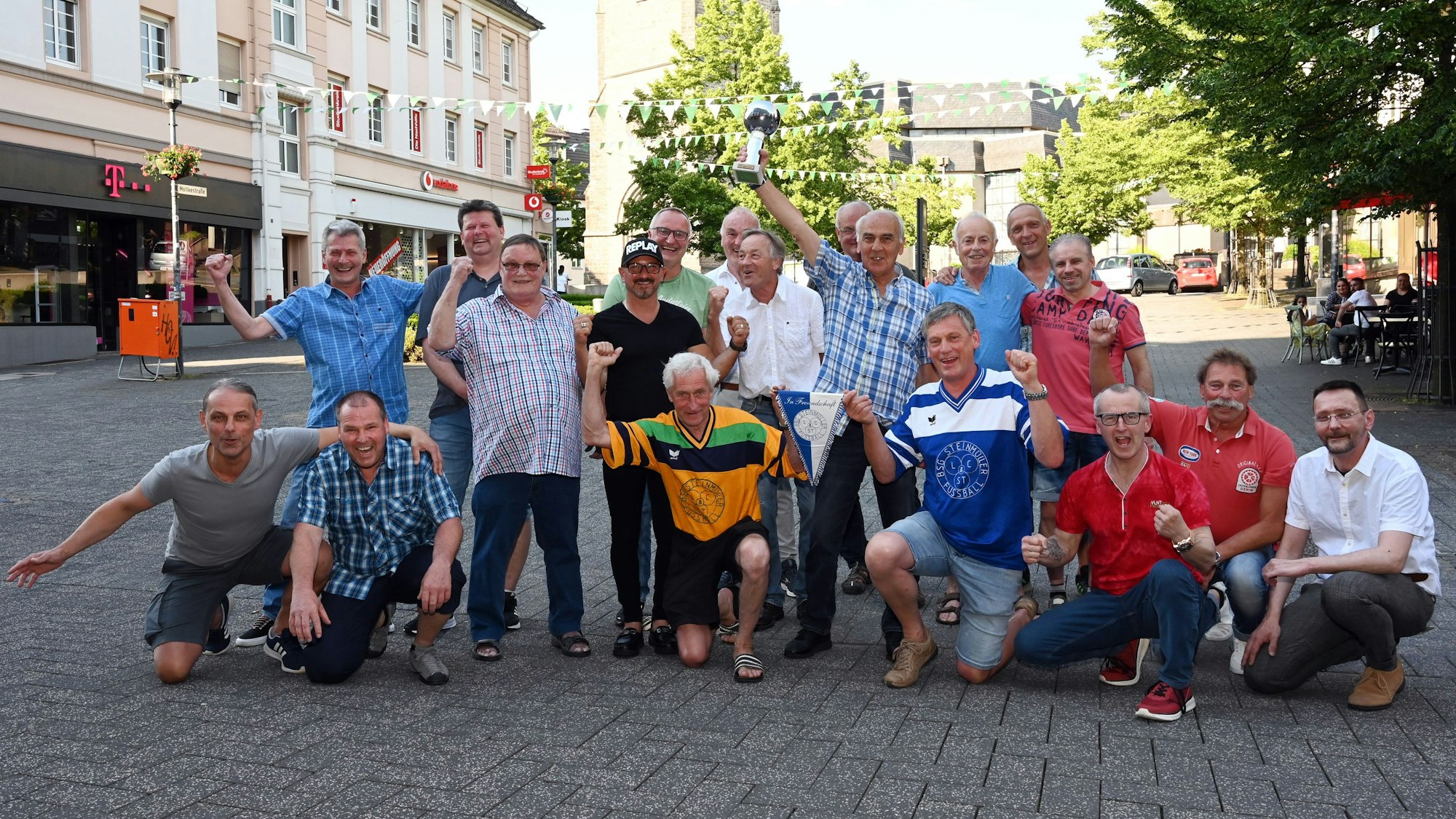 Eine Gruppe Männer posiert für ein Gruppenbild in der Gummersbacher Fußgängerzone. Einer hält einen Pokal in die Höhe.