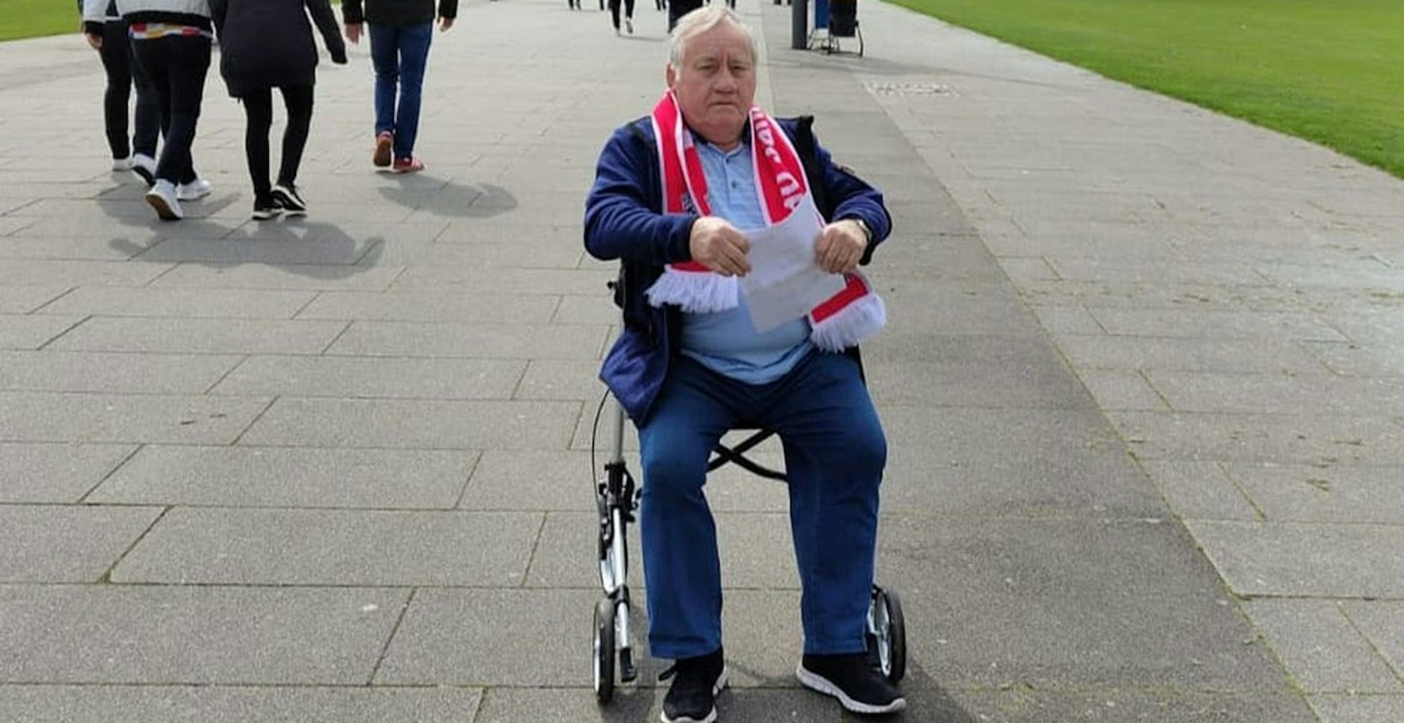 Das Foto zeigt den langjährigen Fußball-Schiedsrichter Willi Hamacher. Weil er nicht mehr so gut zu Fuß ist, greift er auf einen Rollator zurück.