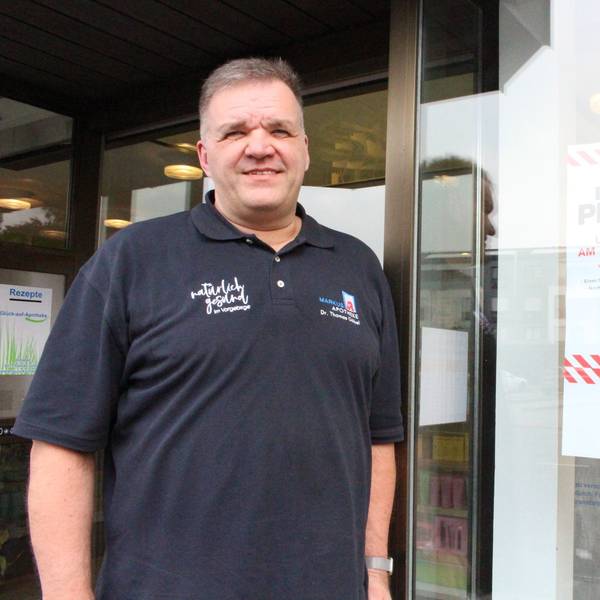 Dr. Thomas Göbel steht vor einer Apotheke.