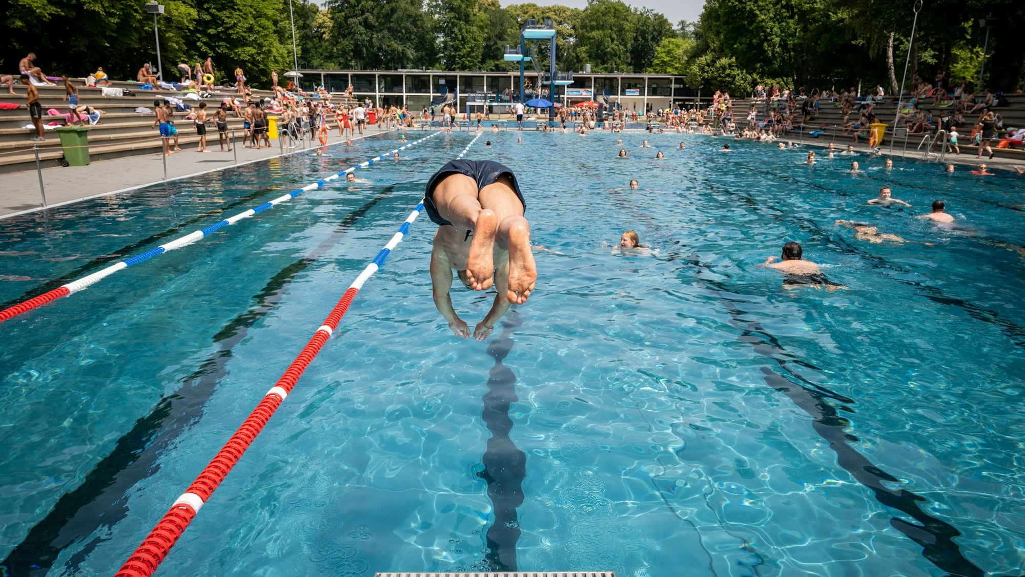 Ein Mann springt im Stadionbad mit einem Kopfsprung vom Bock ins Wasser.