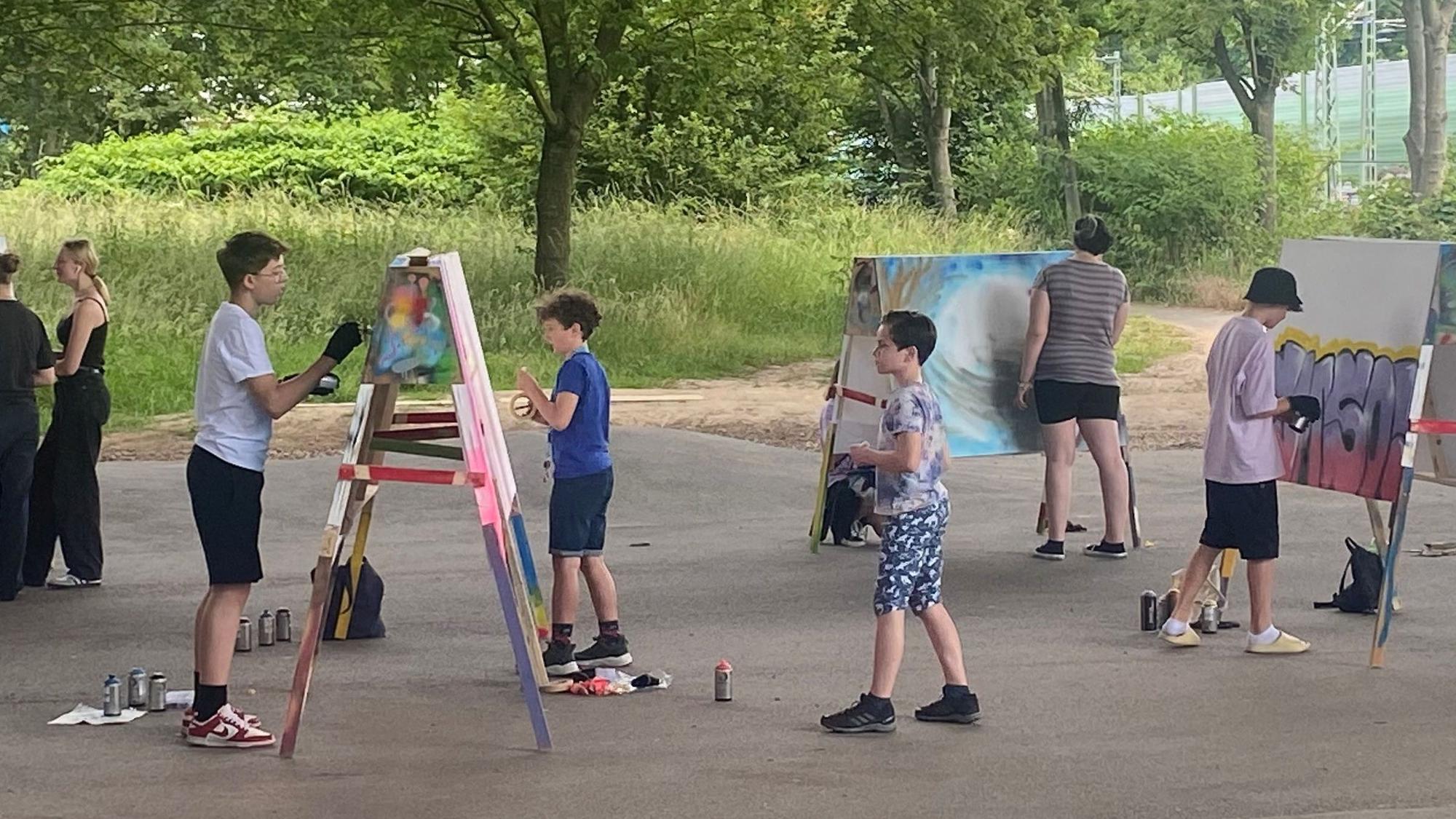 Jugendliche und Kinder vor Leinwänden.