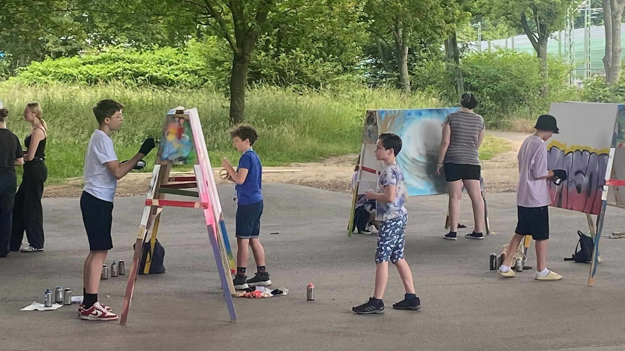 Jugendliche und Kinder vor Leinwänden.