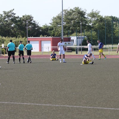 Enttäuschte Fußballer sitzen auf dem Rasen eines Stadions.