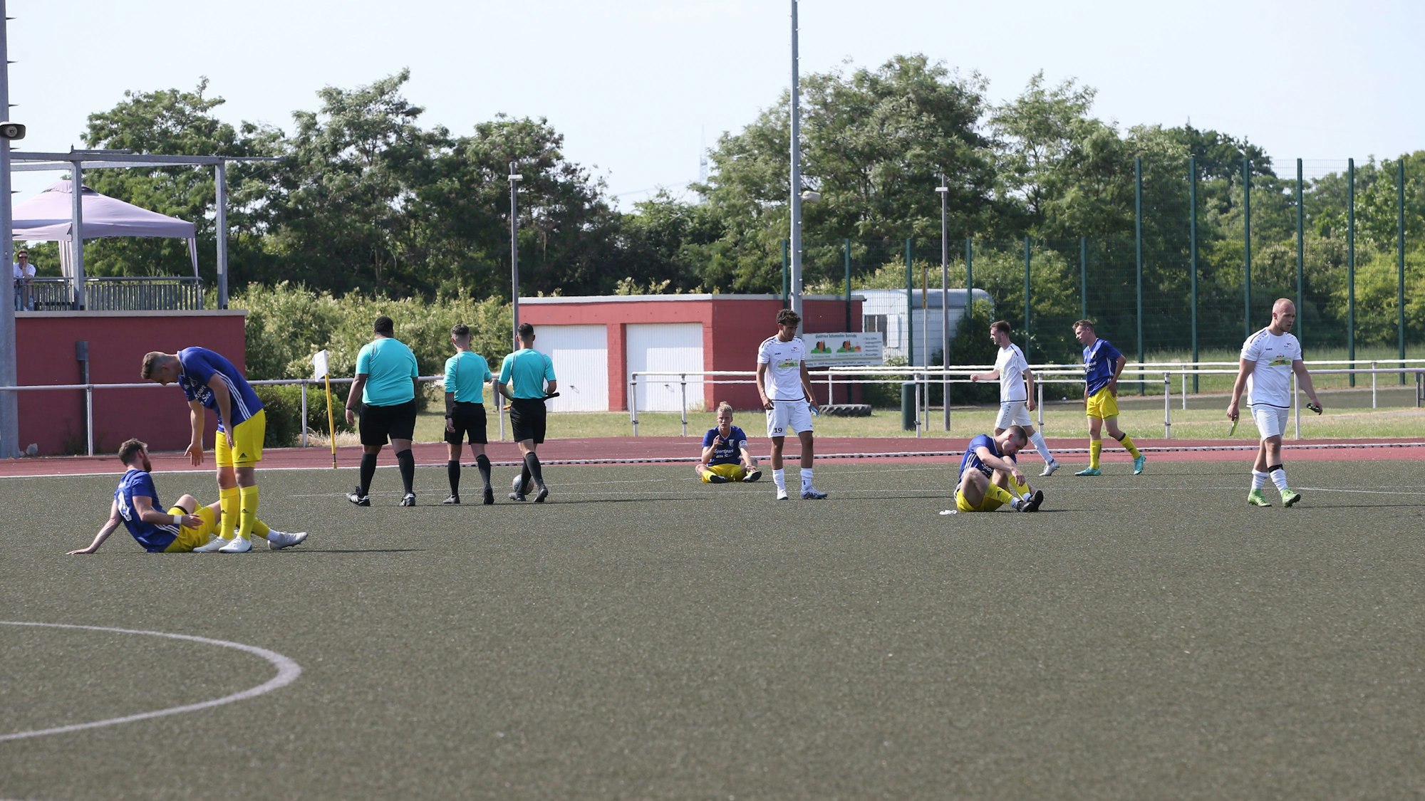 Enttäuschte Fußballer sitzen auf dem Rasen eines Stadions.