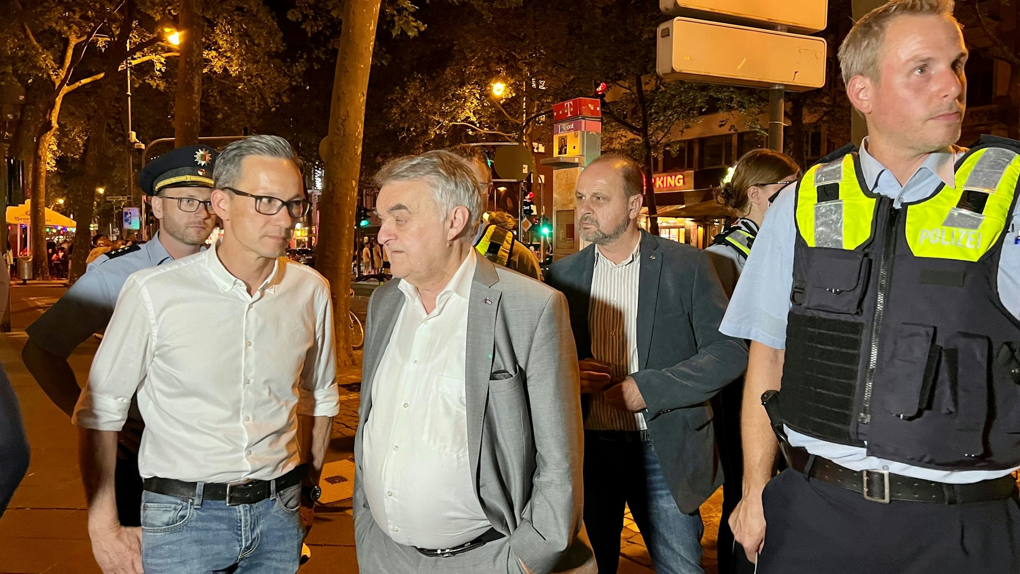 Falk Schnabel und Herbert Reul stehen mit Polizisten auf den Kölner Ringen.