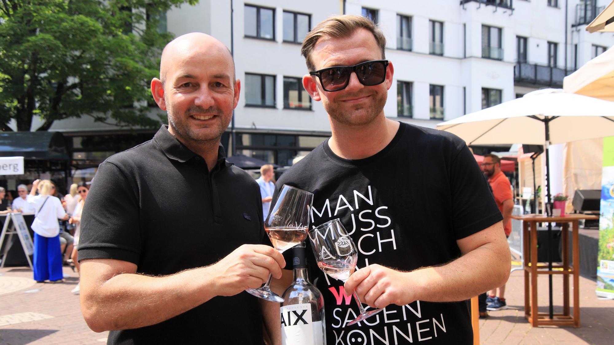 Zwei Männer stoßen mit Weingläsern an.