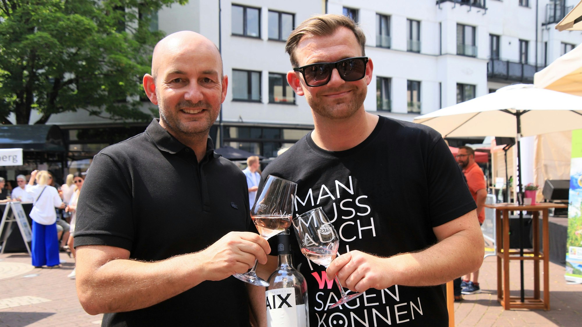 Zwei Männer stoßen mit Weingläsern an.