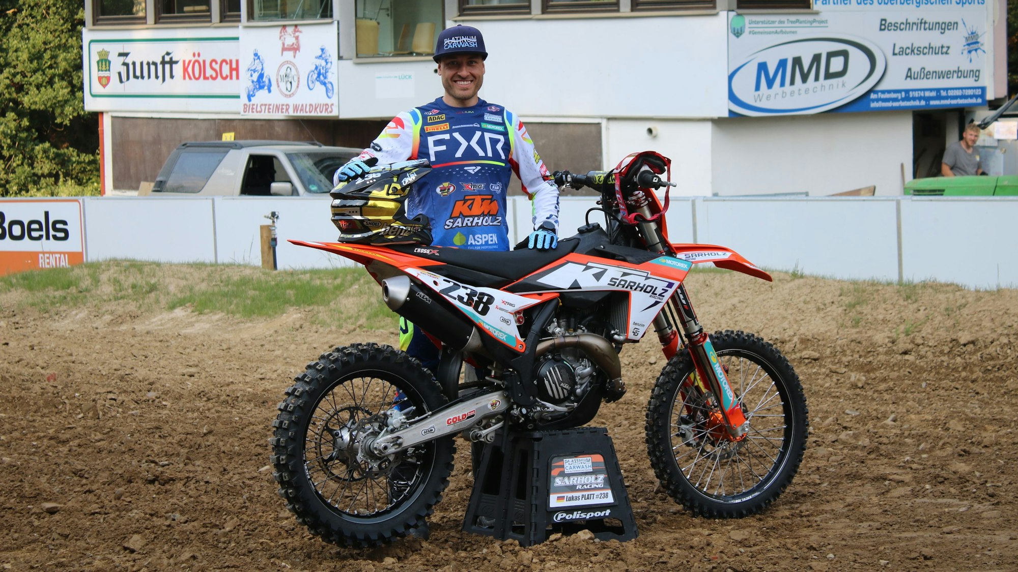 Ein junger Mann steht hinter seinem Motocross-Motorrad.