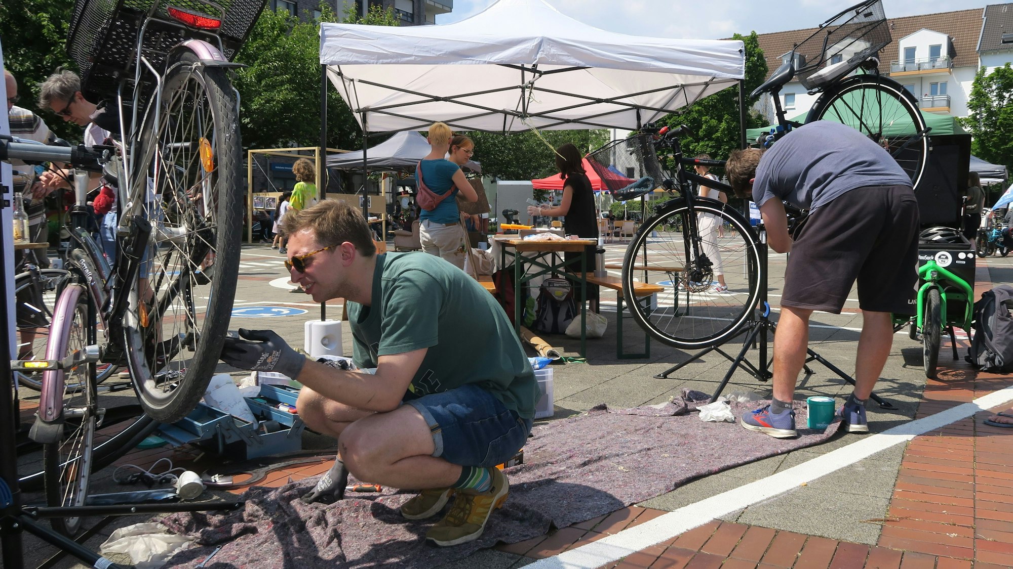 Zwei Männer reparieren ihre Räder an einem Stand des Festivals.