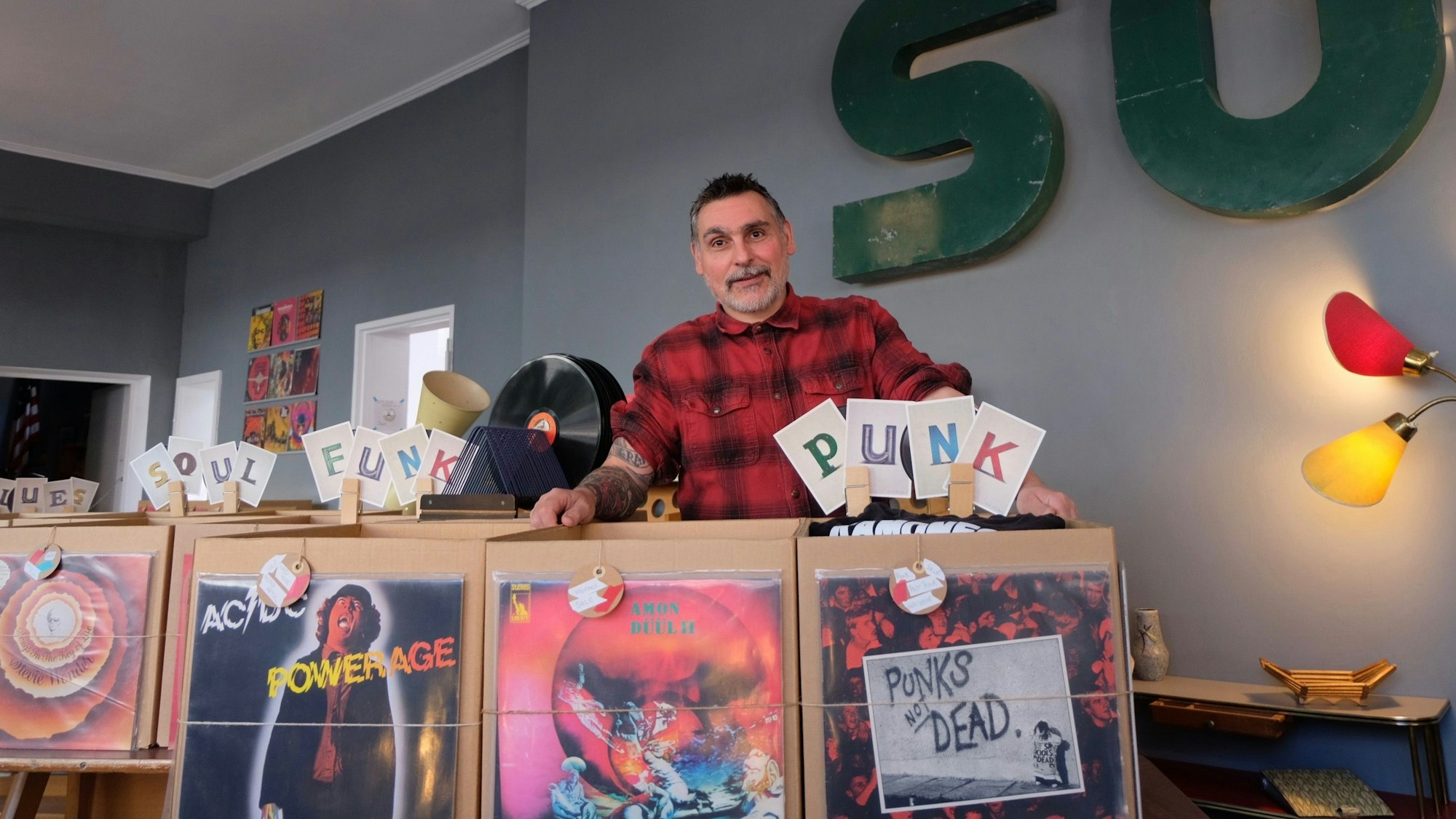 Ein Mann steht hinter Schallplatten.