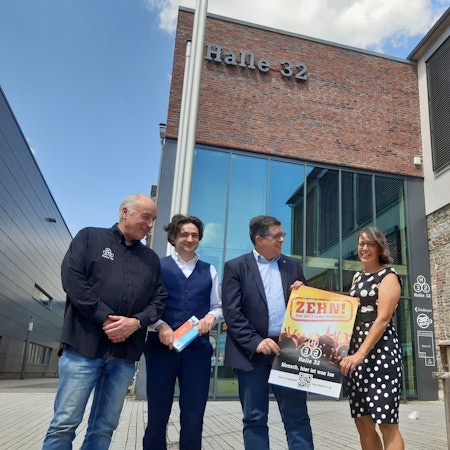 Martin Kuchejda und Ulrike Rösner von der Gummersbacher KultGM, Bürgermeister Frank Helmenstein und Hoteldirektor Alberto Perez an einem Jubiläumsplakat.