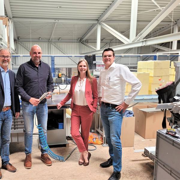 Drei Männer und eine Frau stehen in der Produktionshalle eines Unternehmens in Nettersheim.