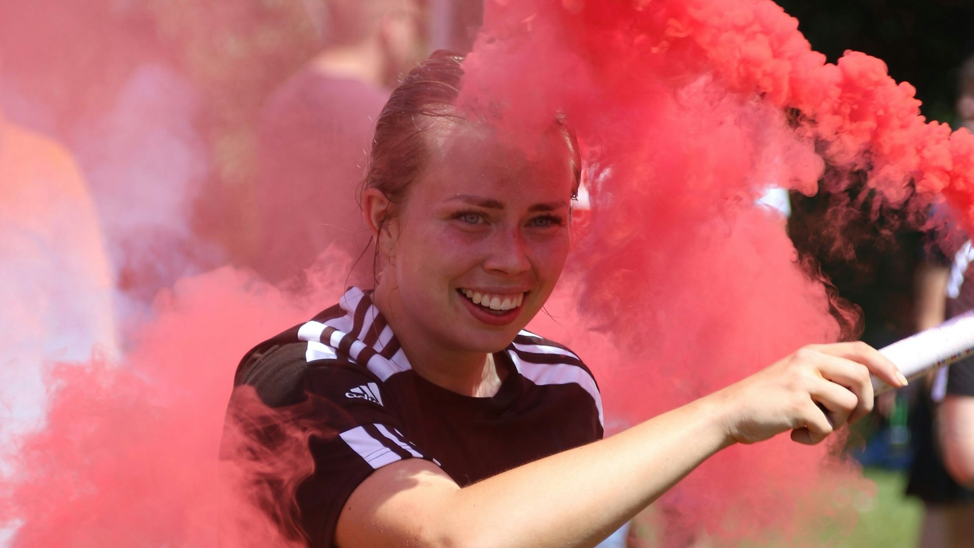 Sina-Marie Sendscheid mit einer bengalischen Fackel, die roten Rauch ausstrahlt.