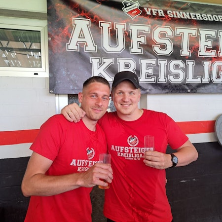 Zwei Fußballer trinken nach dem Aufstieg ein Kölsch.