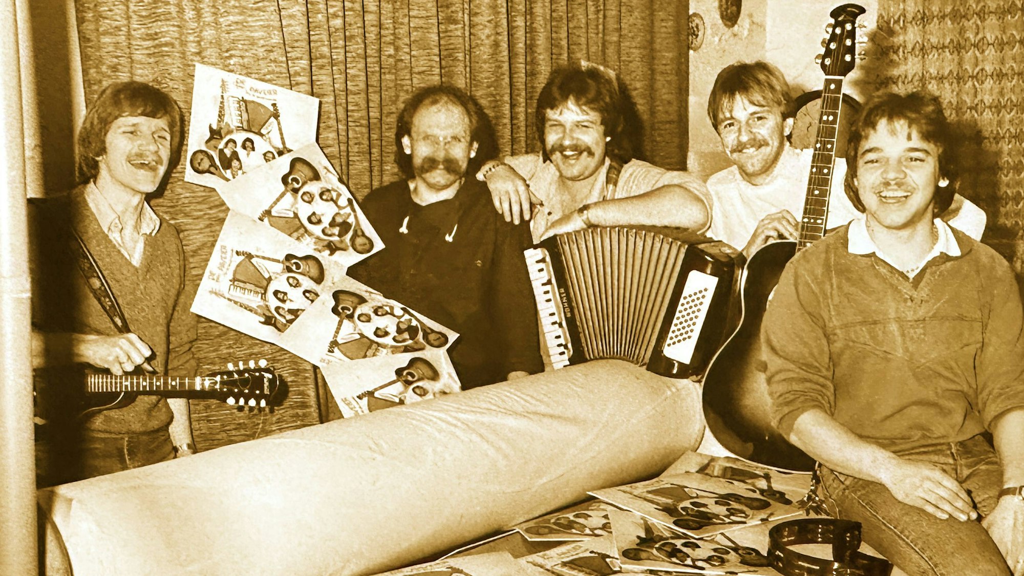 Die Bandmitglieder sitzen mit ihren Instrumenten auf einer Heißmangel.