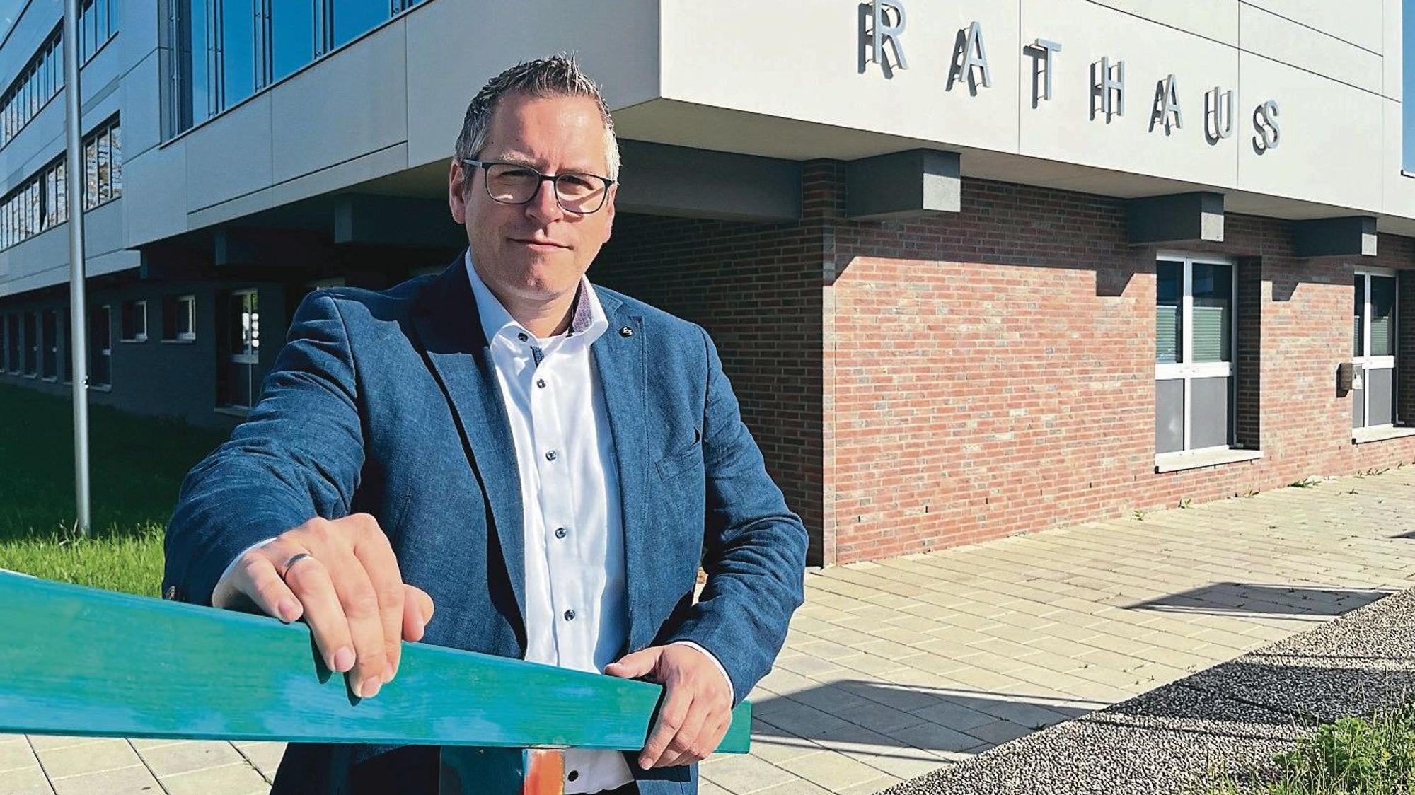 Sascha Solbach (SPD), Bürgermeister von Bedburg, steht hinter einem Treppengeländer vor seinem Rathaus. Solbach hat graues kurzes Haar und trägt eine Brille.