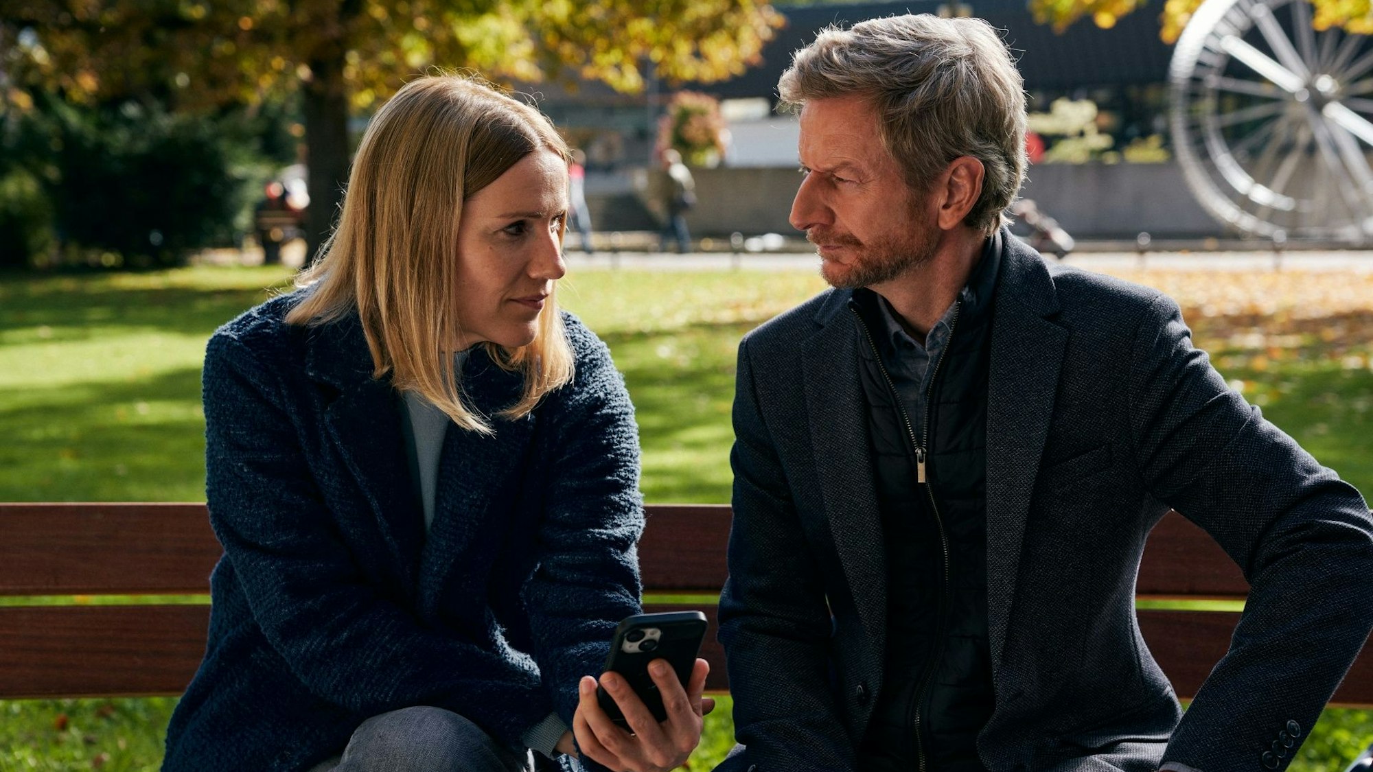 Ein Mann und eine Frau sitzen auf einer Parkbank.