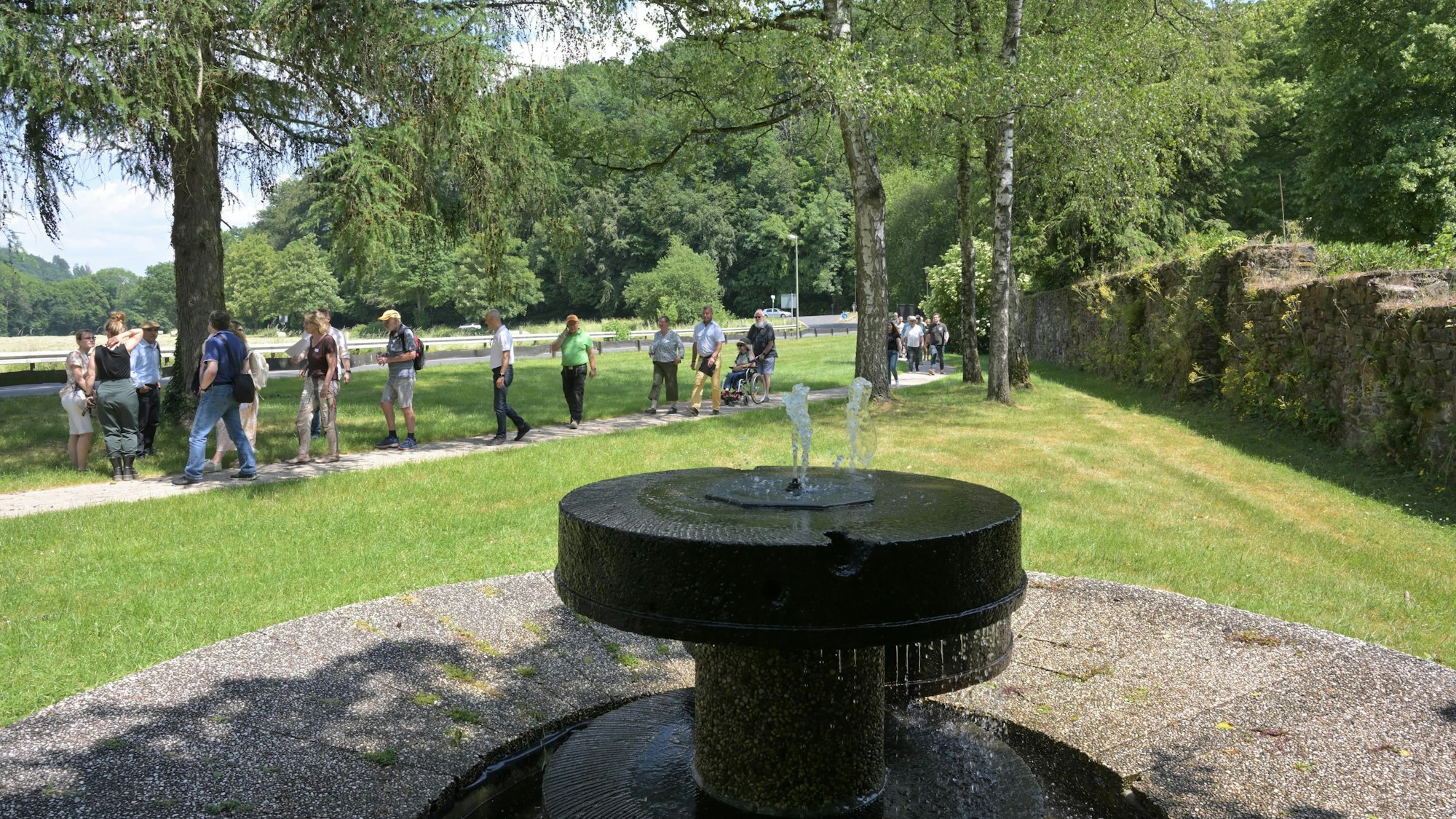 Menschen gehen hinter einem Brunnen her.