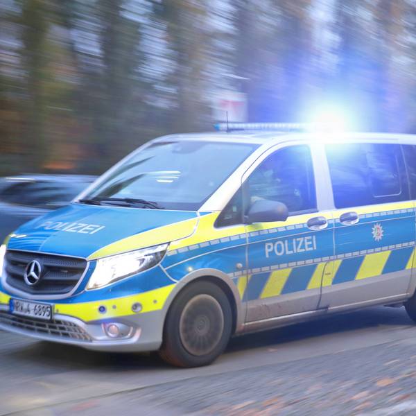 Ein Polizeiauto fährt mit Blaulicht durch eine Straße zum Einsatz.