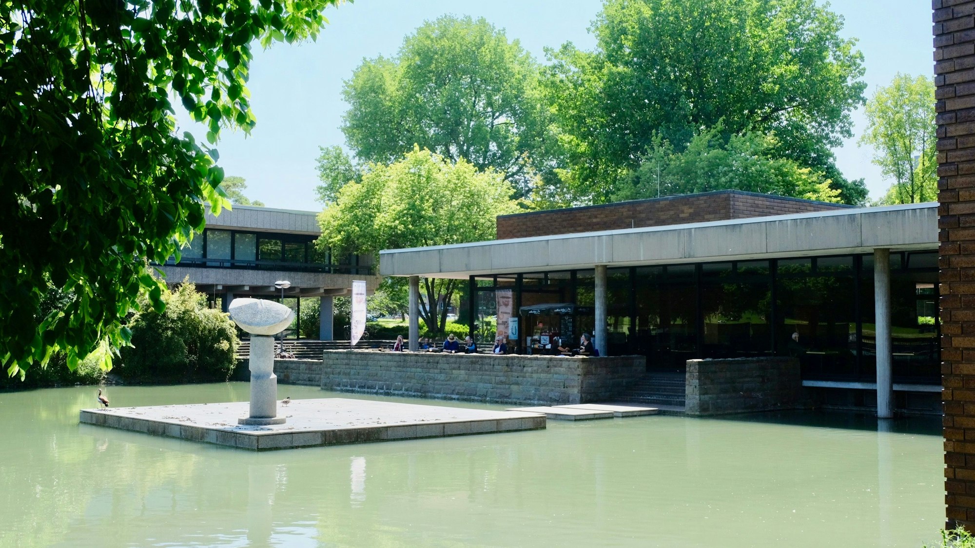 Ein Teich mit dem Museum im Hintergrund.