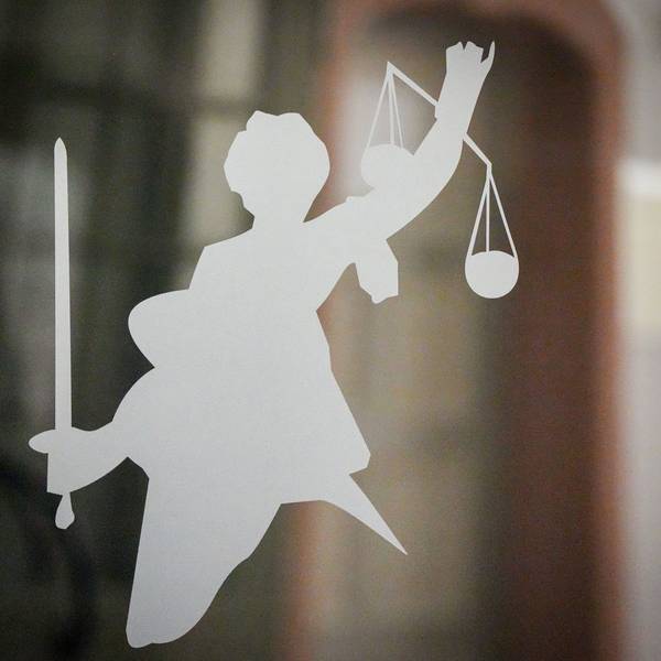 Die Figur der Justitia mit Richtschwert und Waage ist auf dem Glasfenster einer Tür im Gerichtsgebäude zu sehen.