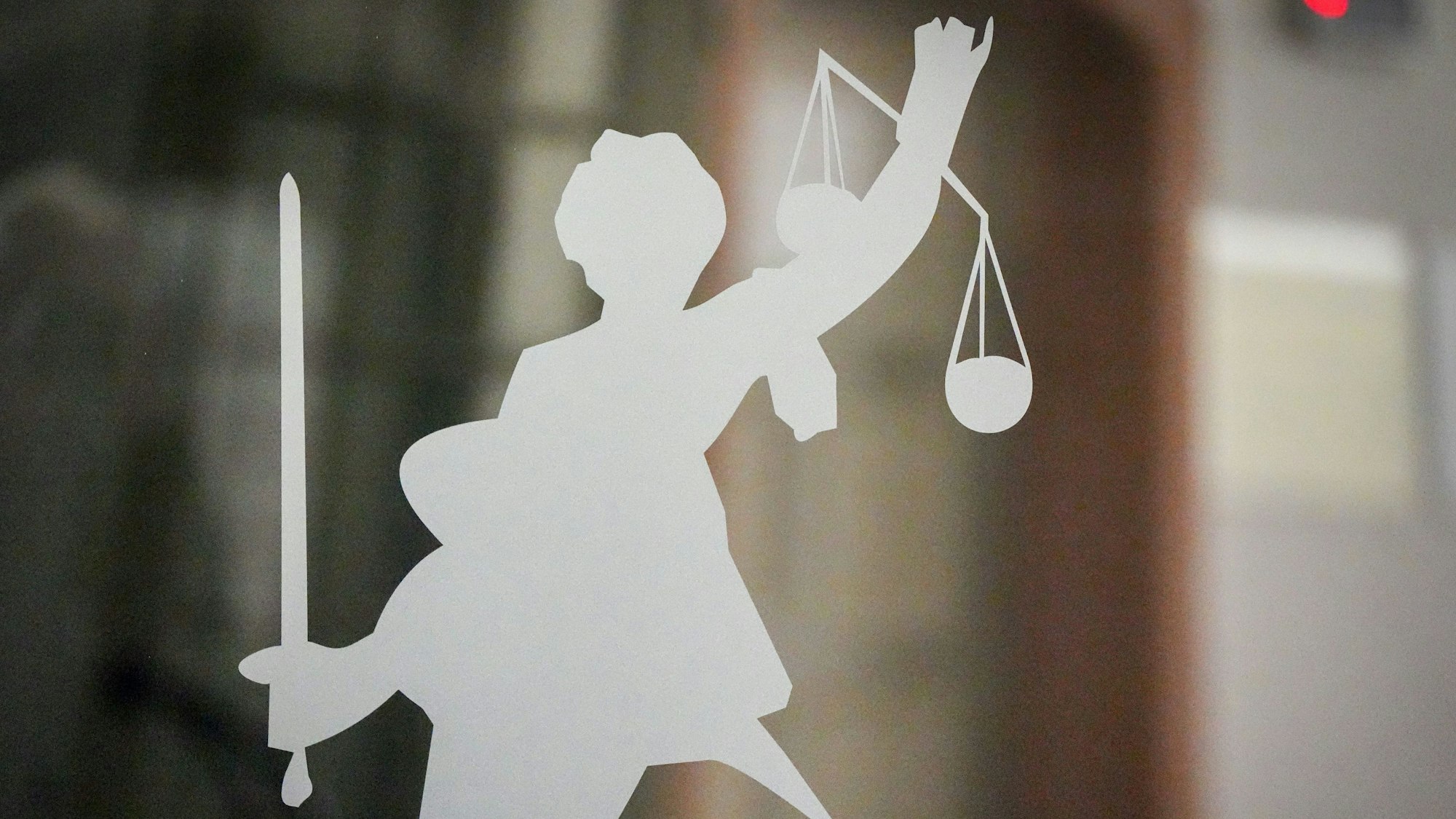Die Figur der Justitia mit Richtschwert und Waage ist auf dem Glasfenster einer Tür im Gerichtsgebäude zu sehen.