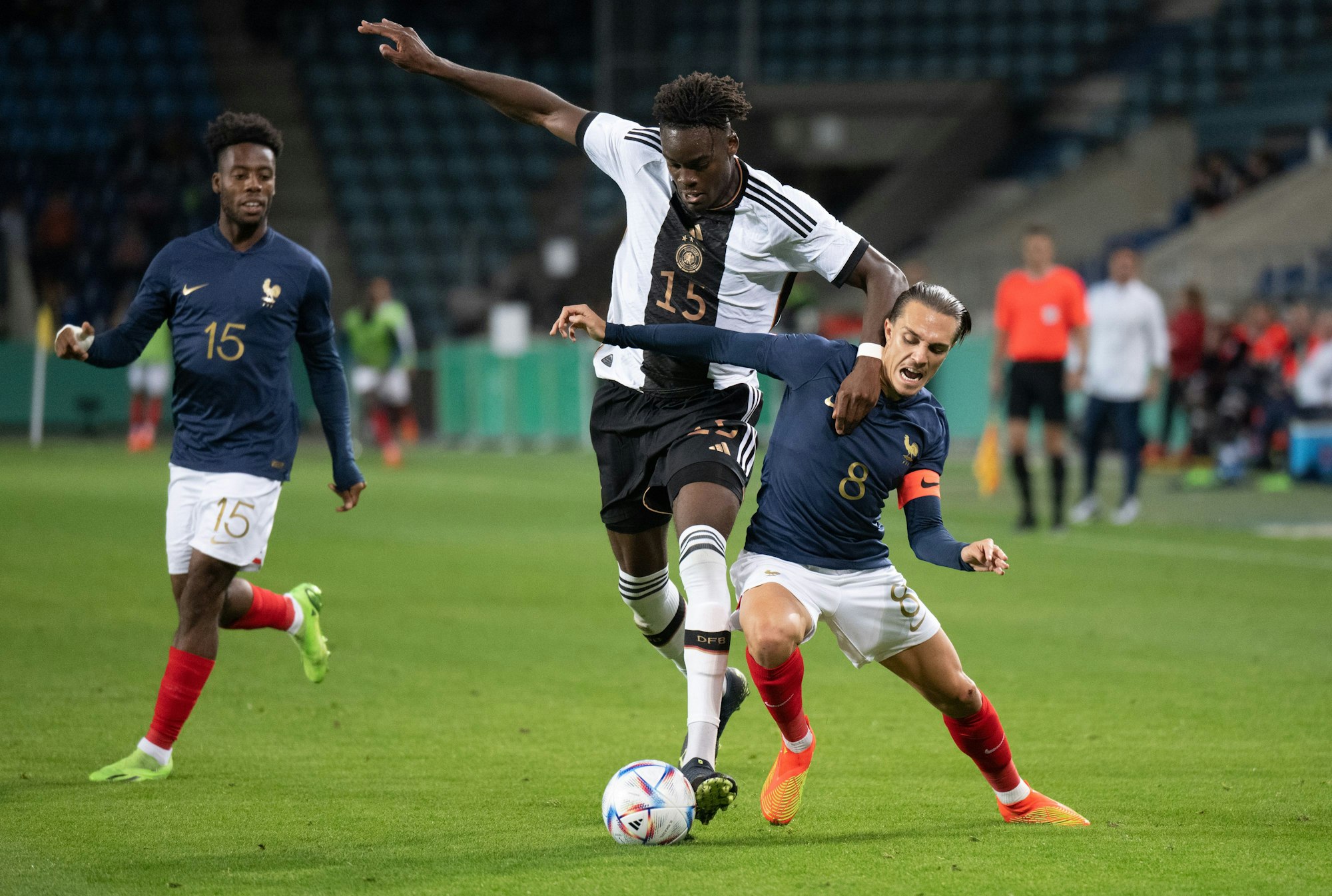 Deutschlands Yann Aurel Bisseck (M) und Frankreichs Maxence Caqueret (r) kämpfen um den Ball.