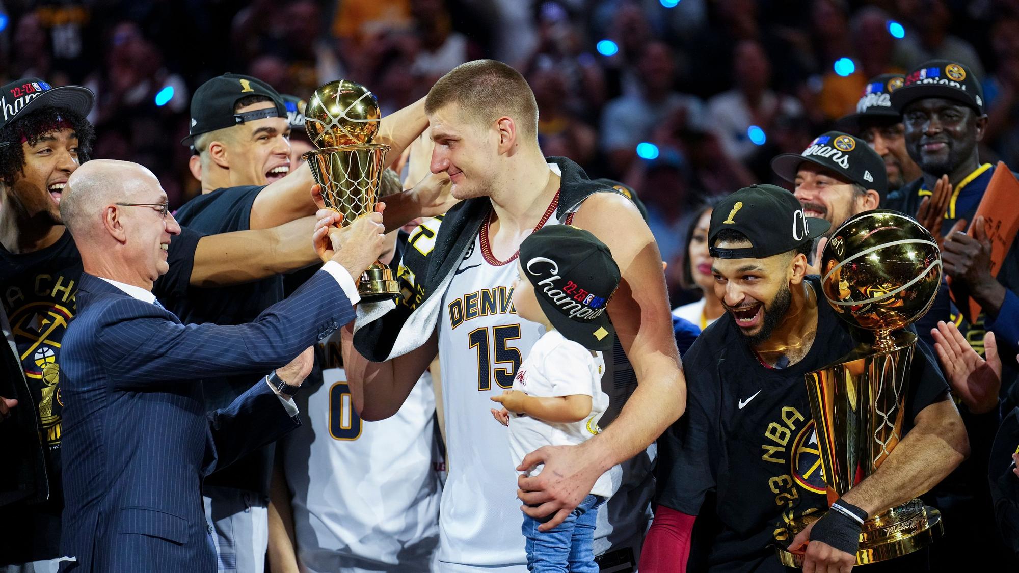 Commissioner Adam Silver (l) überreicht den MVP-Preis an Denver Nuggets-Center Nikola Jokic (M), nachdem das Team die NBA-Meisterschaft gewonnen hat.