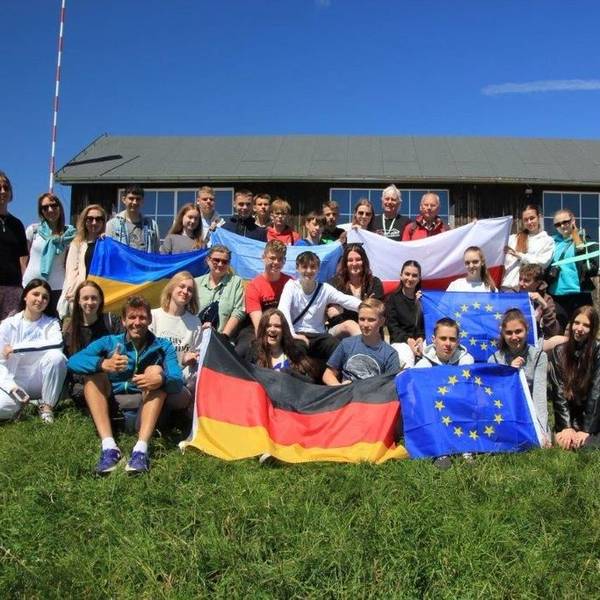 Die Schüler stehen auf dem Rasen und halten viele Fahnen hoch.