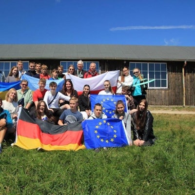 Die Schüler stehen auf dem Rasen und halten viele Fahnen hoch.