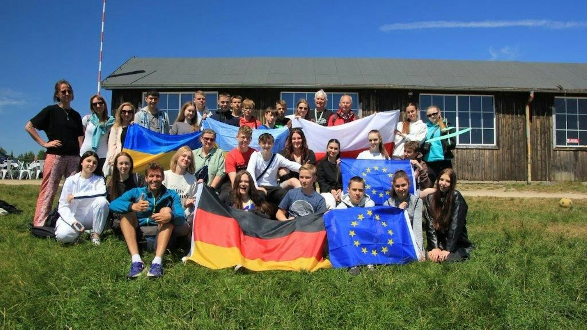 Die Schüler stehen auf dem Rasen und halten viele Fahnen hoch.