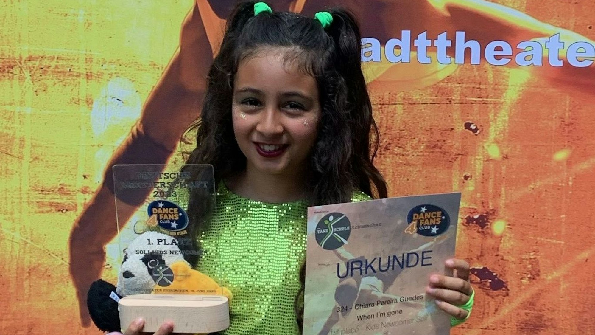Das Bild zeigt eine junge Tänzerin, die eine Siegerskulptur und eine Urkunde in den Händen hält.