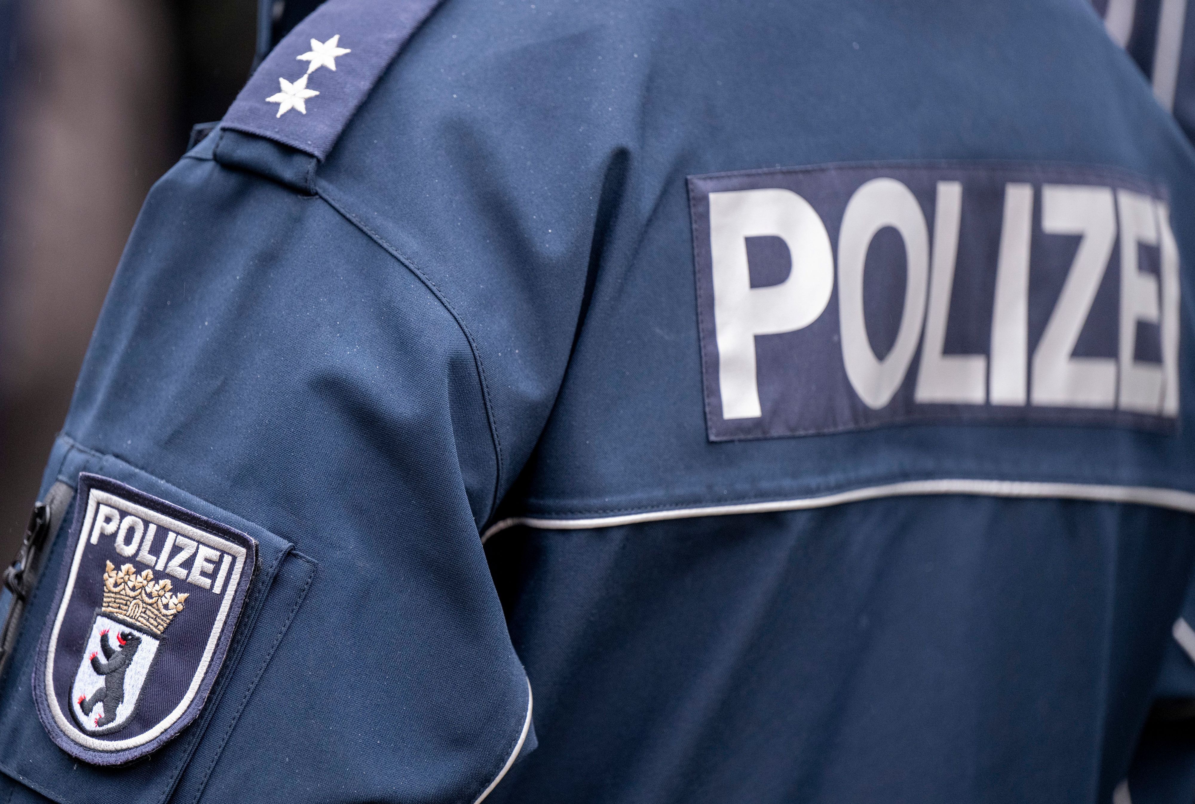Die Aufschrift Polizei und der Wappen von Berlin der Uniform eines Polizeibeamten.