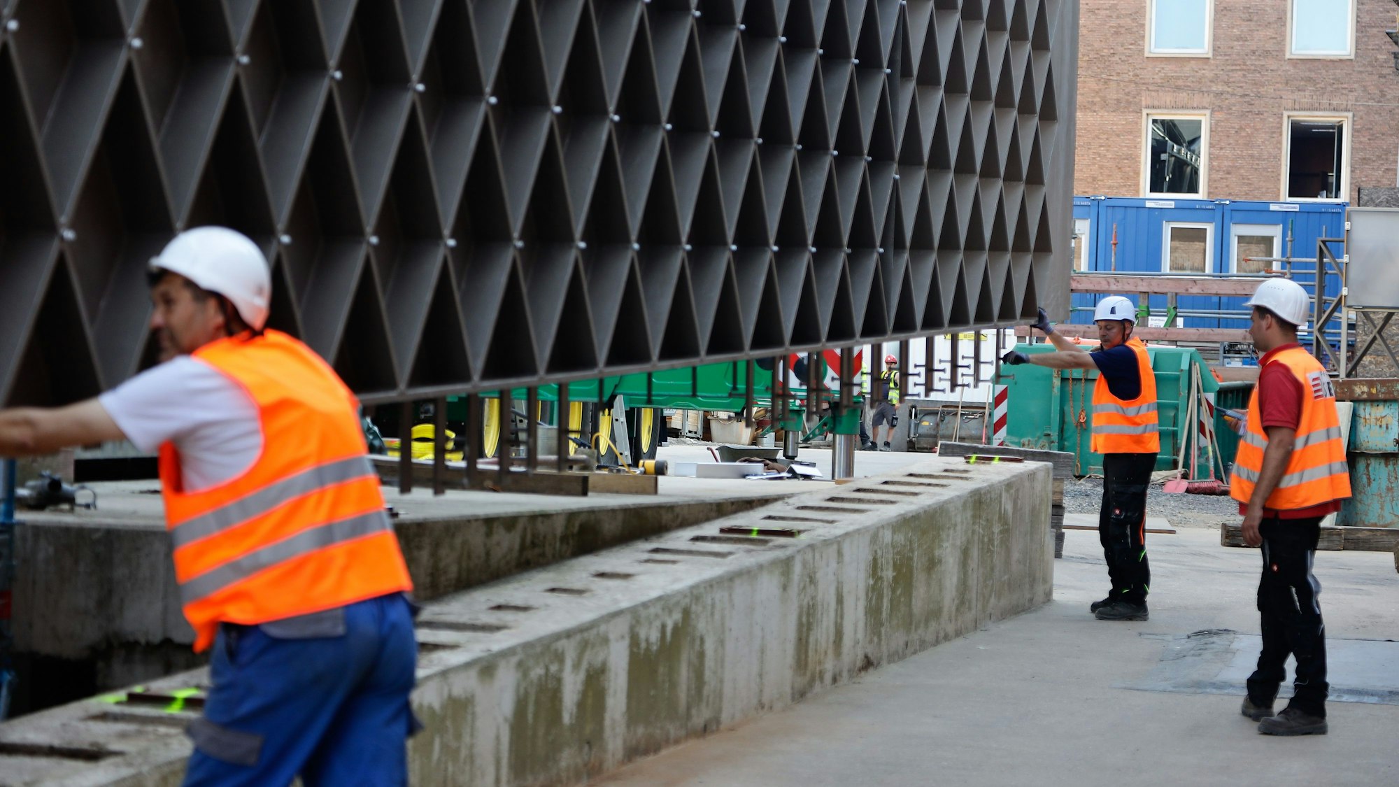 Bauarbeiter bauen ein Stahlelement auf einen Betonsockel für das Jüdische Museum in Köln