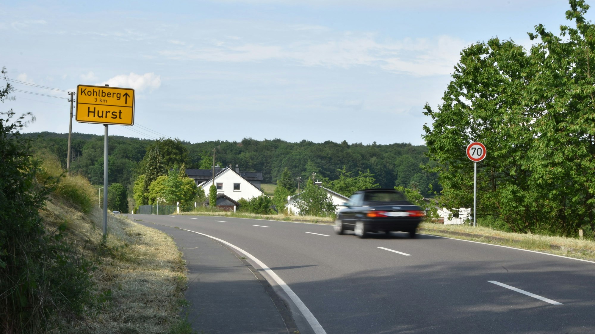 Ein Auto fährt über eine Landstraße.