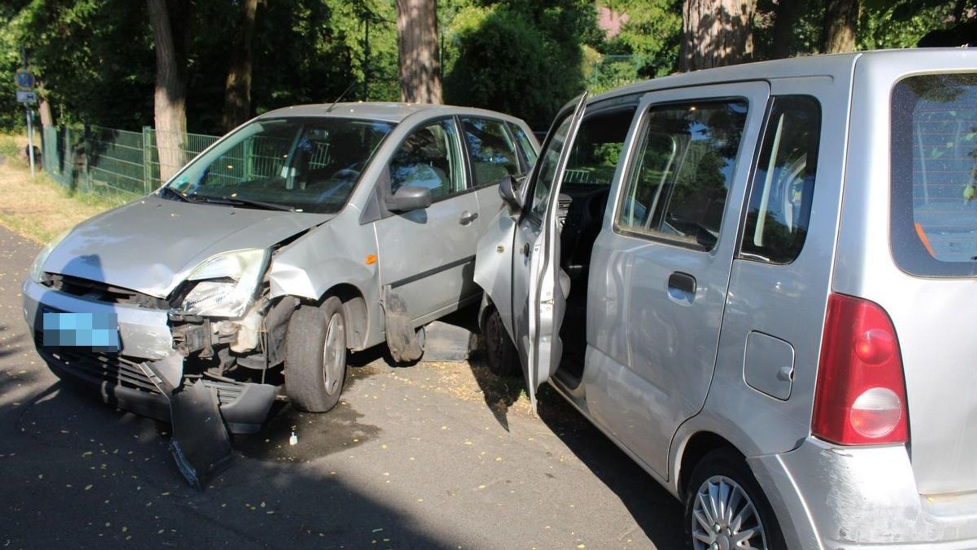 Zwei beschädigte Autos stehen auf einer Straße.