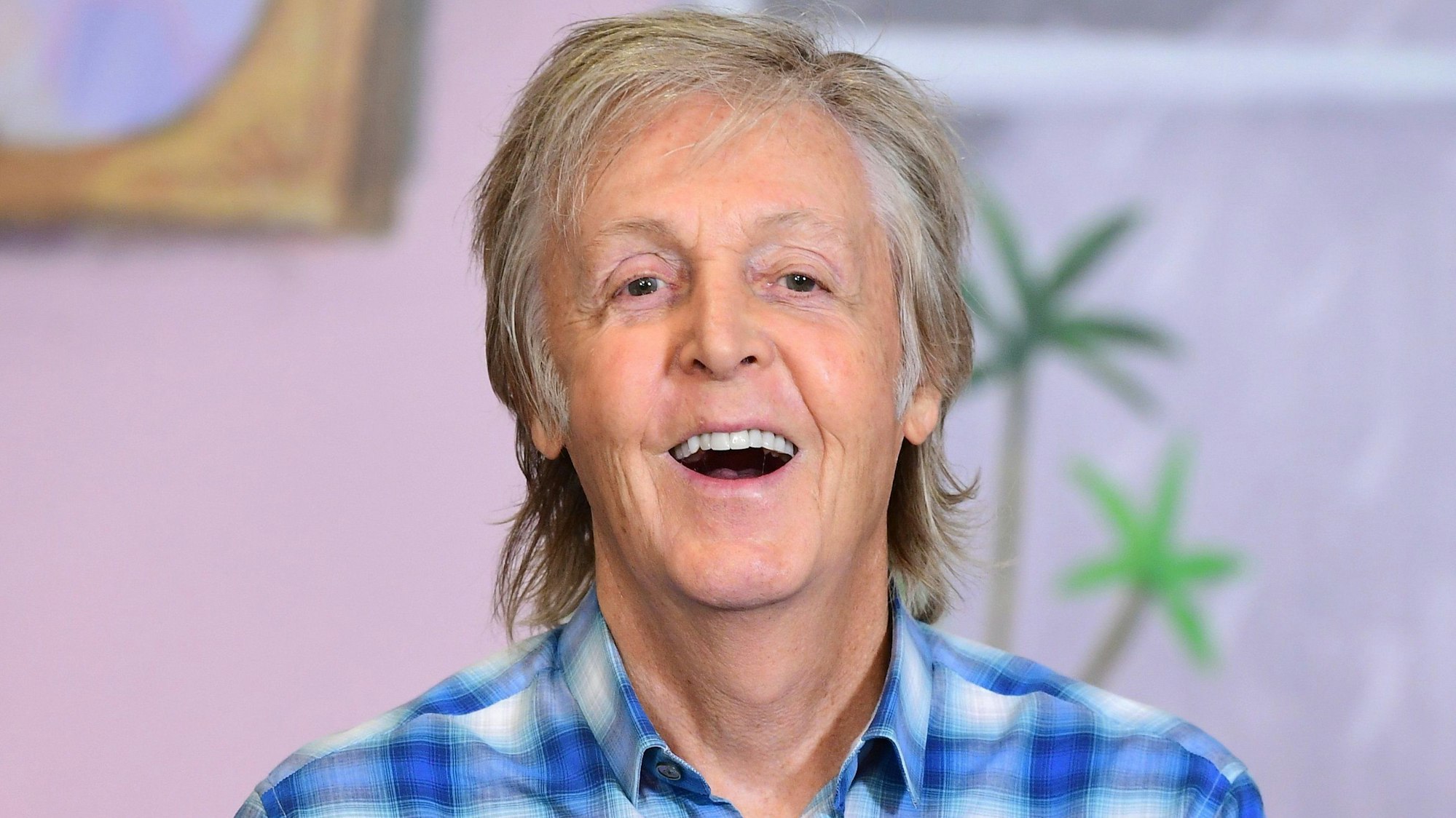 Paul McCartney, Musiker aus Großbritannien, lacht bei der Vorstellung eines Kinderbuches. Er trägt ein blau-weiß kariertes Hemd.