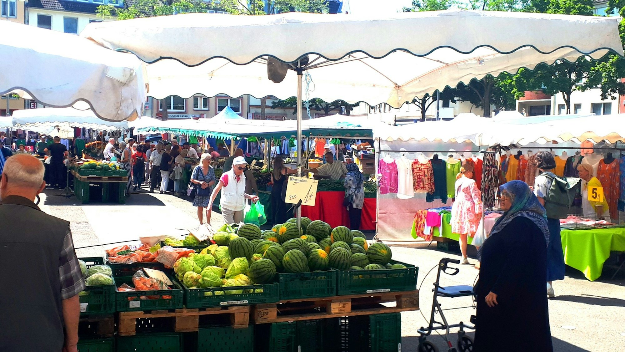 Auf dem Markt in Nippes stehen viele verschiedene Stände und Menschen bummeln.