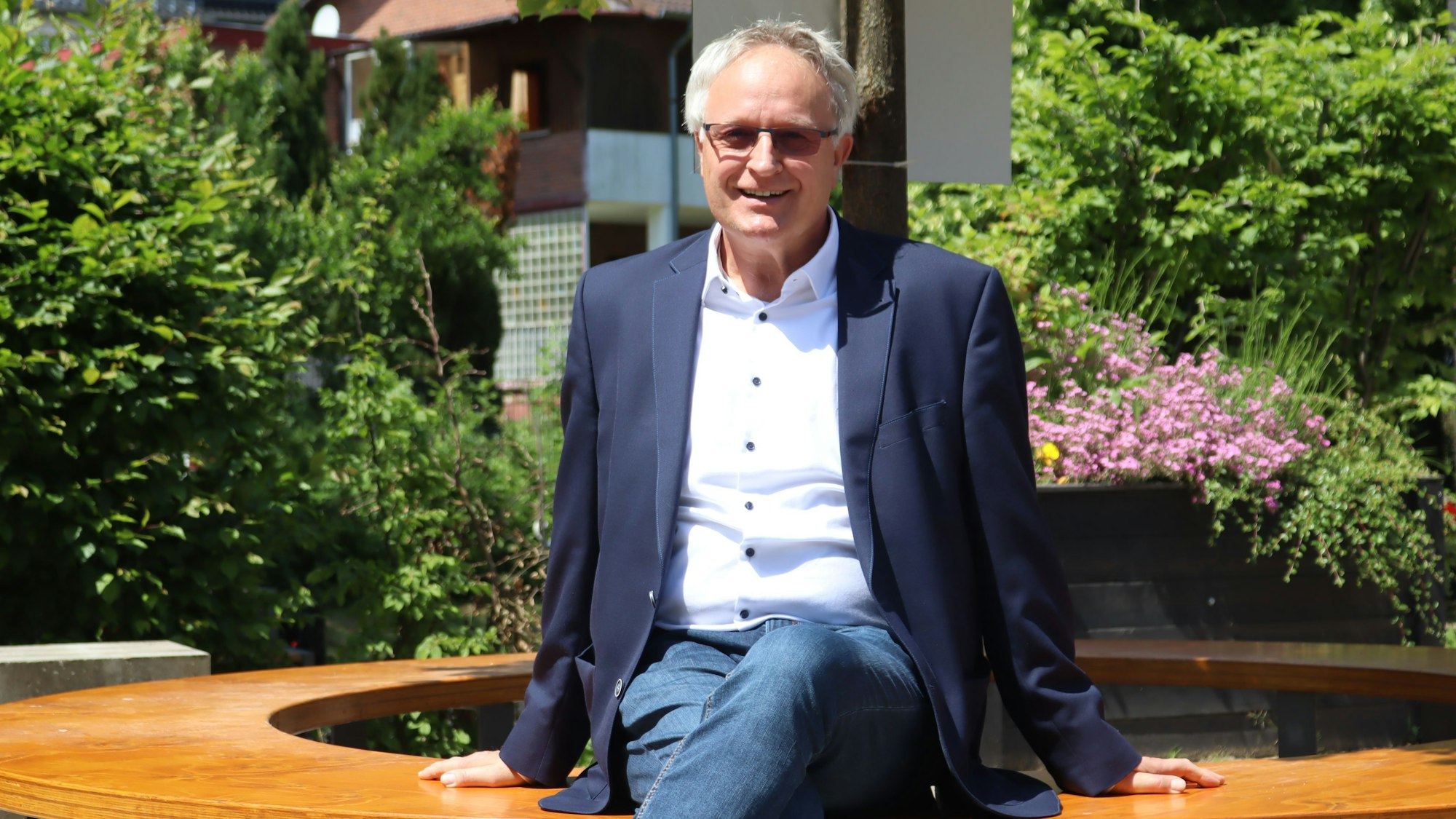 Bernhard Helfer sitzt auf einer der Bänke im neu gestalteten Außenbereich der Schule.